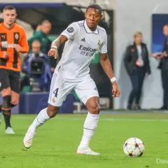 Piłkarz Realu Madryt w białej koszulce z numerem 4, David Alaba, prowadzi piłkę. W tle widać zawodnika Szachtara Donieck w pomarańczowej koszulce. To obraz jednego z najlepszych obrońców świata.