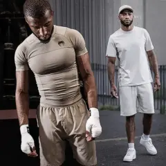 Dwóch mężczyzn w strojach sportowych. Jeden w beżowym rashguardzie i spodenkach, drugi w jasnej koszulce i spodenkach. Rashguard co to? To idealna odzież do treningów.