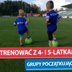 Dwóch chłopców w strojach piłkarskich na boisku, przygotowujących się do treningów piłki nożnej dla dzieci.